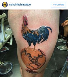 a rooster on top of a globe tattoo