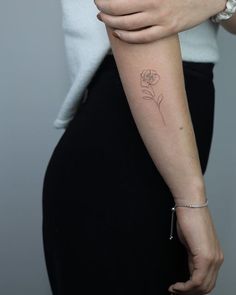 a woman's arm with a small flower tattoo on the left side of her arm