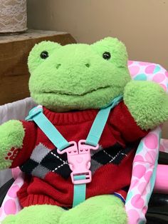 a green stuffed frog sitting on top of a chair