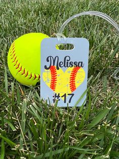 a baseball and ball are sitting in the grass with a name tag attached to it