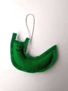 a green felt banana ornament hanging on a white wall with a string attached to it