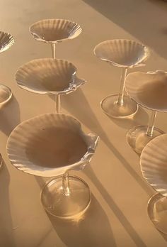 several wine glasses are lined up on a table with plates in the shape of seashells