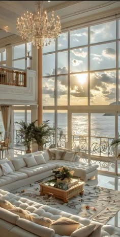 a living room filled with lots of furniture and large windows overlooking the ocean at sunset