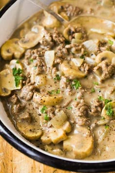 a close up of a bowl of food with meat and mushrooms in gravy