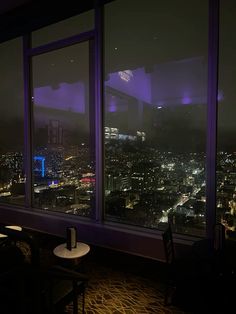 the city lights are lit up at night as seen from an office building's window