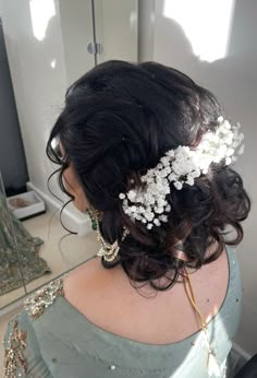 the back of a woman's head with flowers in her hair and pearls on it