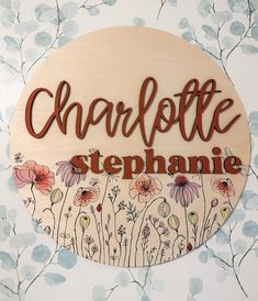 a wooden sign that says charlotte stephanie surrounded by flowers