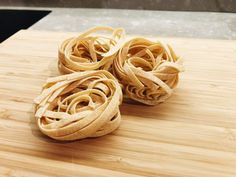 three uncooked noodles on a wooden cutting board