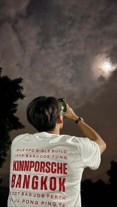 a man is looking up at the sky with his cell phone to see the moon