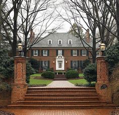 a large brick house with steps leading up to the front door and trees in the background