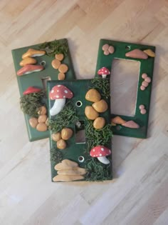 two green light switch plates with mushrooms and moss growing on them, sitting on a wood floor