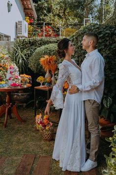 a man and woman standing next to each other in front of some potted plants