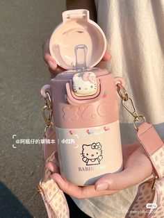 a person holding a hello kitty water bottle in their hand with a pink strap around it