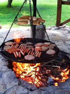 hot dogs and hamburgers are being cooked on an outdoor grill with chains hanging over it