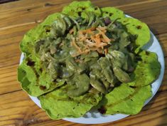 a white plate topped with lettuce covered in sauce