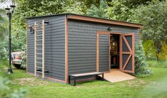 a small gray shed sitting on top of a lush green field