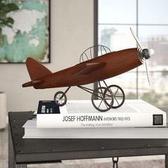 a model airplane sitting on top of a stack of books next to a book case