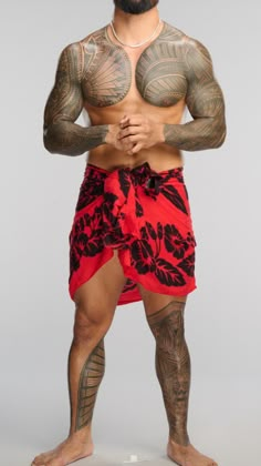 a man with tattoos on his chest and arms, wearing a red swim trunks while standing in front of a gray background