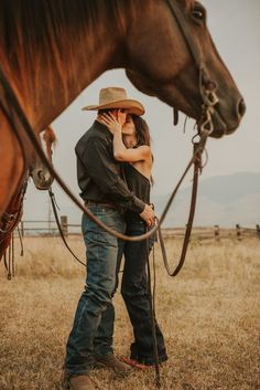 a man and woman standing in front of a brown horse with their heads touching each other