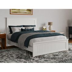 a white bed sitting on top of a rug next to a wooden table and chair