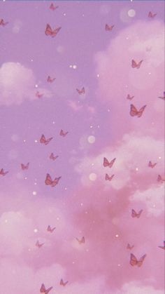 there are many small butterflies flying in the sky with pink and blue clouds behind them