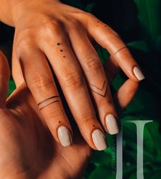 a woman's hand with two small tattoos on her fingers and the other half of her finger