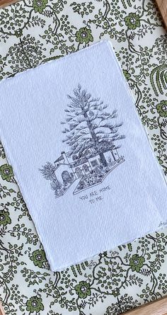 a napkin with a drawing of a pine tree on it sitting in front of a green and white wallpaper