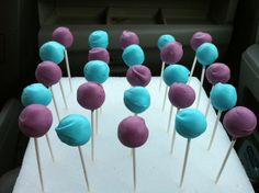 cake pops with blue and pink frosting are on a white tray in the back seat of a car