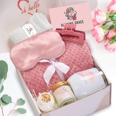 an open pink box with some items in it next to flowers and soaps on a table