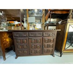 an old wooden cabinet sitting next to a mirror and other antique furniture in a store