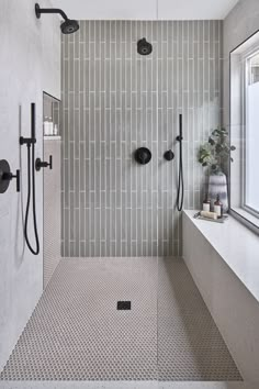 a walk in shower sitting next to a bath tub under a window with two faucets