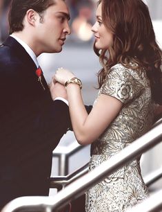 a man and woman standing next to each other in front of an escalator