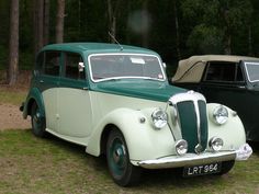 an old green and white car parked next to each other in front of some trees