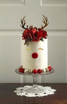 a white cake with red flowers and antlers on top, sitting on a table