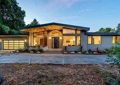 a modern home in the evening with lights shining on it's windows and doors