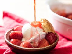 a bowl filled with ice cream and strawberries on top of a red table cloth