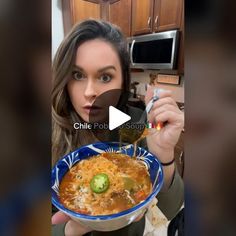 a woman holding a bowl of food in front of her face and looking at the camera