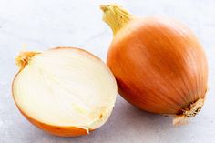 an onion is cut in half on the counter top next to it's peel