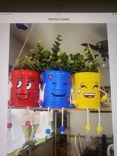 three buckets with plants in them hanging from the ceiling and smiling faces on them