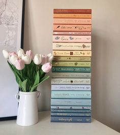 a white vase filled with flowers next to a stack of books