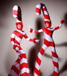 two people dressed in red and white striped costumes, one holding the other's hand