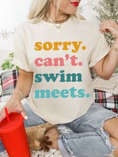 a woman sitting on the floor wearing a t - shirt that says sorry, can't swim meets