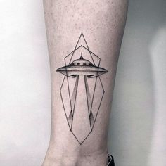 a black and white photo of a person's leg with a spaceship tattoo on it