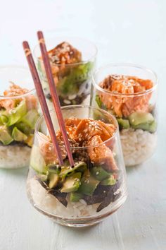 three glasses filled with food and chopsticks on top of rice