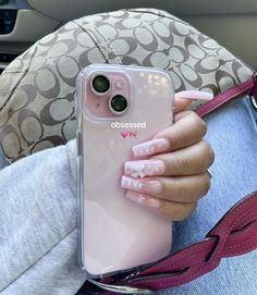 a person holding a pink phone case in their hand while sitting on a car seat