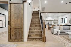 a living room filled with furniture next to a wooden stair case and open door that leads to the second floor