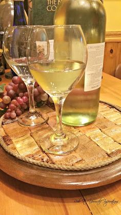 two wine glasses sitting on top of a cork coaster next to a bottle of wine