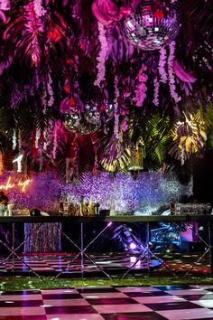 an elaborately decorated stage is lit up at night with lights and flowers hanging from the ceiling