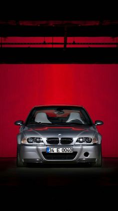 a silver car parked in front of a red wall