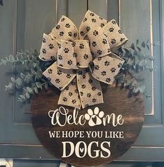 a welcome sign hanging on the side of a door with a dog's bow